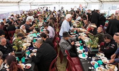 A group of people eating together at long tables in a marquee.