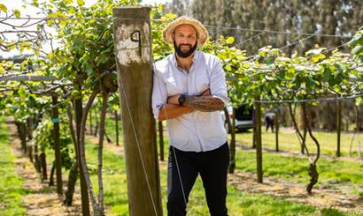 Man leaning against a post in an orchard.