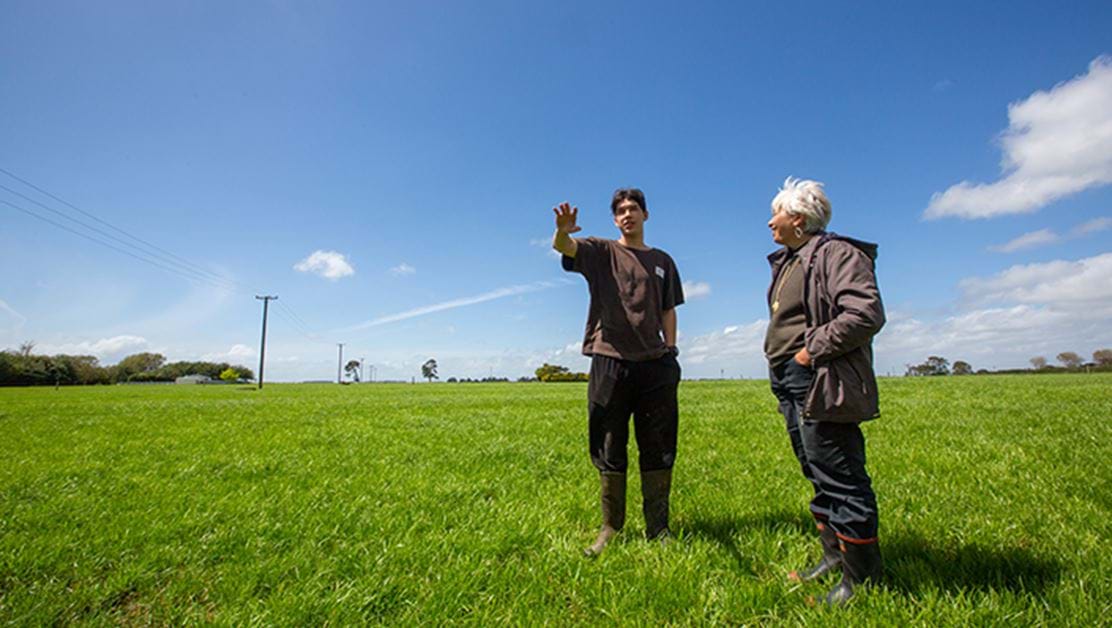 Two people standing in a field having a conversation.